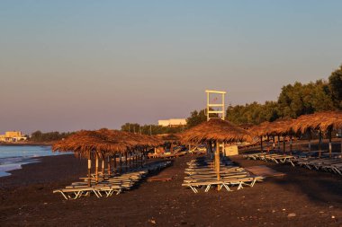 Vlichada 'da kıyıları ve denizi olan güzel, siyah bir sahil. Mavi gökyüzü arka planında beyaz bulutlar ve deniz var..