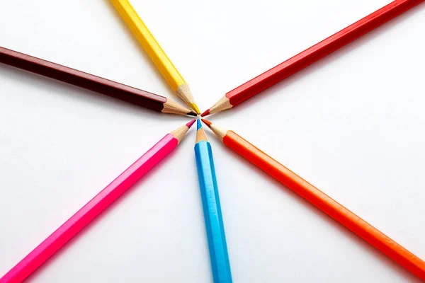 Colored crayons on a white background. The crayons are brown, black, yellow, orange, blue, purple.