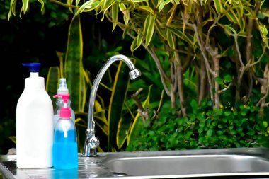 New normal, Refill hand soap and alcohol gel bottles on stainless steel sink for washing and cleaning hands at school in Thailand to prevent and protect germs and coronavirus which is spreading now. clipart