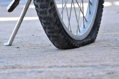 Kaldırımdaki patlak bisiklet lastiğinin yakın görüntüsü.