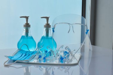 Şeffaf plastik yüz bakımı, yeşil dezenfektanlar ve cam kapının önündeki yeşil tıbbi maske. Yüze ve ellere sürtünmek için. Antikoronavirüs ya da covid-19 konsepti..