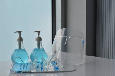 Şeffaf plastik yüz bakımı, yeşil dezenfektanlar ve cam kapının önündeki yeşil tıbbi maske. Yüze ve ellere sürtünmek için. Antikoronavirüs ya da covid-19 konsepti..