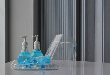 Şeffaf plastik yüz bakımı, yeşil dezenfektanlar ve cam kapının önündeki yeşil tıbbi maske. Yüze ve ellere sürtünmek için. Antikoronavirüs ya da covid-19 konsepti..