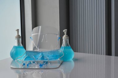 Şeffaf plastik yüz bakımı, yeşil dezenfektanlar ve cam kapının önündeki yeşil tıbbi maske. Yüze ve ellere sürtünmek için. Antikoronavirüs ya da covid-19 konsepti..