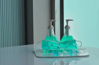 Şeffaf plastik yüz bakımı, yeşil dezenfektanlar ve cam kapının önündeki yeşil tıbbi maske. Yüze ve ellere sürtünmek için. Antikoronavirüs ya da covid-19 konsepti..