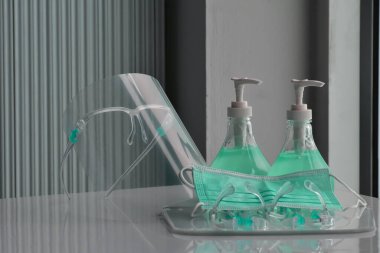 Şeffaf plastik yüz bakımı, yeşil dezenfektanlar ve cam kapının önündeki yeşil tıbbi maske. Yüze ve ellere sürtünmek için. Antikoronavirüs ya da covid-19 konsepti..
