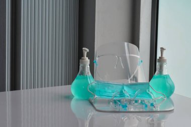 Şeffaf plastik yüz bakımı, yeşil dezenfektanlar ve cam kapının önündeki yeşil tıbbi maske. Yüze ve ellere sürtünmek için. Antikoronavirüs ya da covid-19 konsepti..