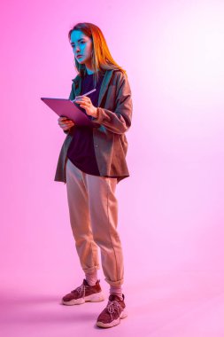 Laptoplu modern kız, tablet bilgisayar. Özgür yaratıcılık. Genç blogcu ev idaresi yapıyor. Renkli Neon ışığı ve arkaplan.