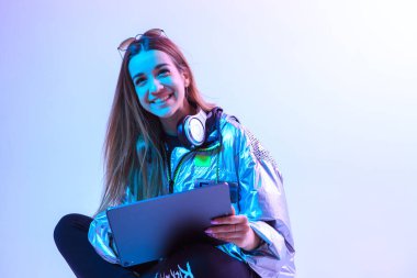 Laptoplu modern kız, tablet bilgisayar. Özgür yaratıcılık. Genç bir blogcu İçişleri Bakanlığı yapıyor. Renkli Neon ışığı ve arkaplan.