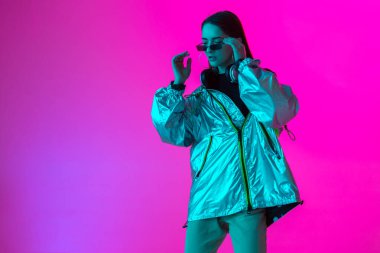 Stüdyoda renkli neon bir arka planda dans eden zarif genç bir kız. Müzik poster tasarımı.