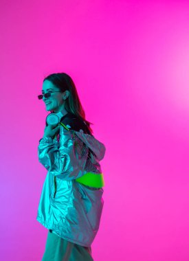 Stüdyoda renkli neon bir arka planda dans eden zarif genç bir kız. Müzik poster tasarımı.