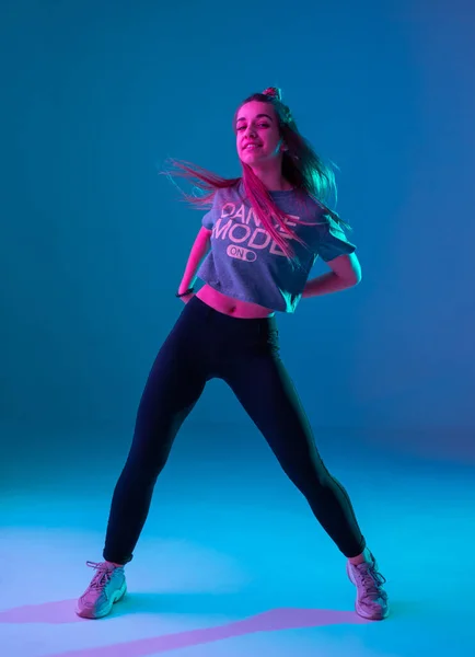 Chica joven y elegante bailando zumba en el estudio sobre un fondo de neón de color. Diseño de cartel de danza . — Foto de Stock