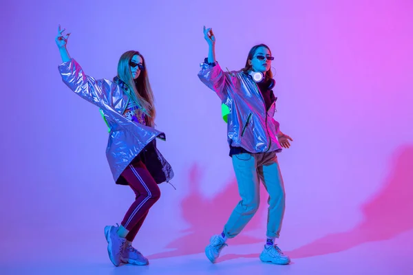 Jonge stijlvolle meisjes dansen in de Studio op een gekleurde neon achtergrond. Muziek dj poster ontwerp. — Stockfoto