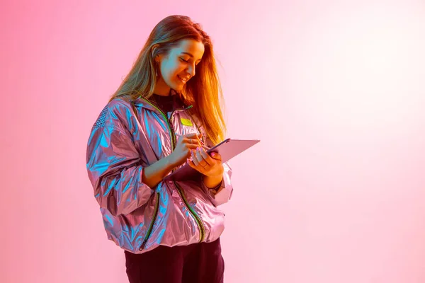 Chica moderna con ordenador portátil, tableta. Libre creatividad. Un joven bloguero hace una oficina en casa. Luz de neón de color . —  Fotos de Stock