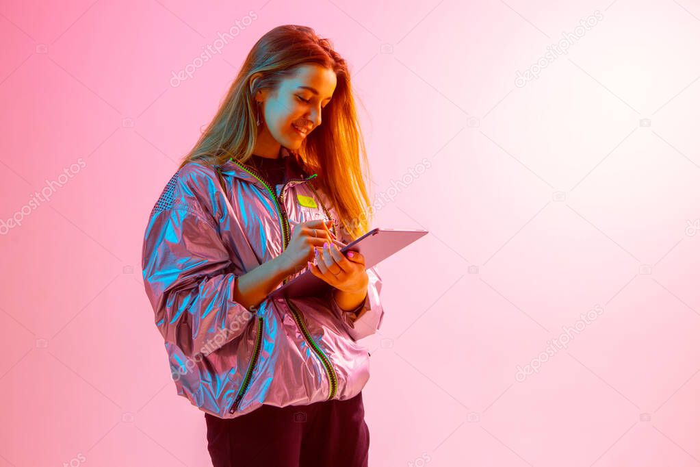 Modern Girl with laptop, tablet computer. Free creativity. A young blogger makes a Home office. Colored Neon light.