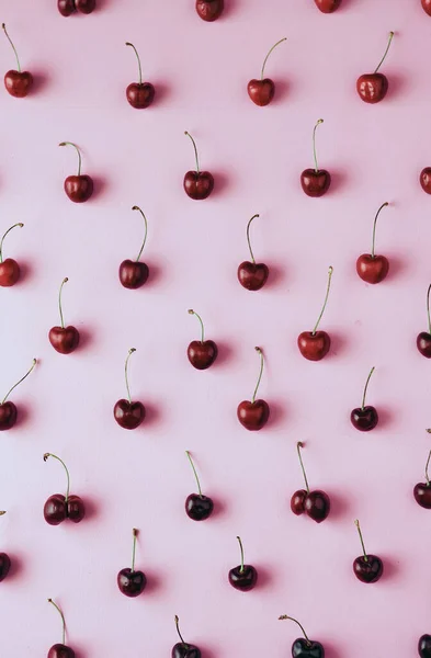 Frische Kirschbeeren sind in einem Muster auf fliederfarbenem Hintergrund mit sanftem Licht und Schatten ausgelegt, ein helles Poster. — Stockfoto