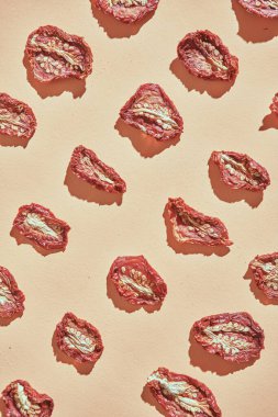 Güneşli İtalya 'dan gelen güneşte kurutulmuş domatesler bej arka planda tekrar tekrar sıralanır. yemek posteri.