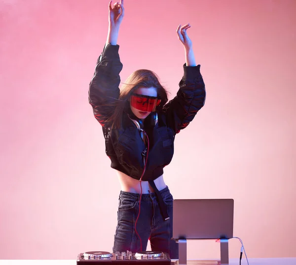 Stílusos lány DJ szemüvegben fejhallgató és egy bombázó keveri zene táncol egy partin a neon fény a füst . — Stock Fotó
