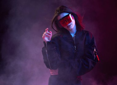 Gözlüklü, ceketli, dumanlı bir gece kulübünde dans eden şık bir kız..