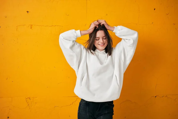 Retrato de una joven estudiante guapa con capucha blanca, ropa casual contra una pared de hormigón naranja . —  Fotos de Stock