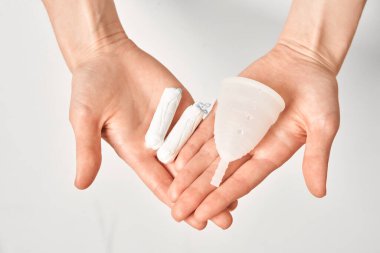 Çevre dostu, yumuşak, aybaşı bardağı ve beyaz arka planda izole edilmiş ellerde tamponlar. 