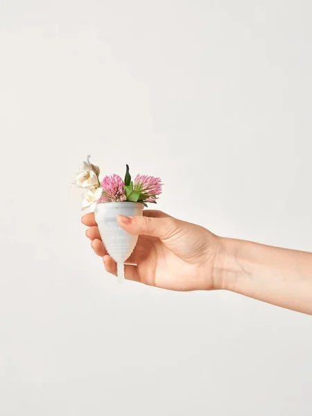 Coupe menstruelle en silicone blanc doux respectueux de l'environnement avec des fleurs chez les filles isolées à la main sur fond rose — Photo