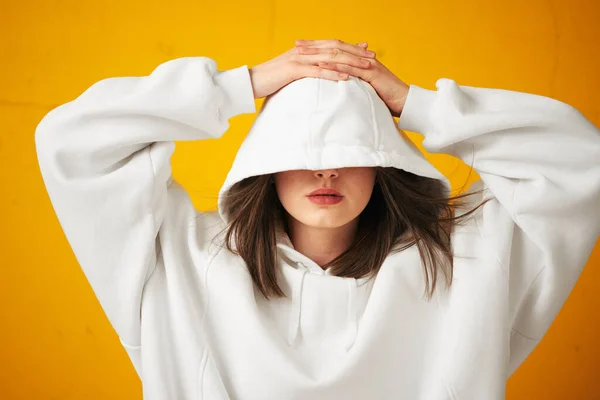 Porträt einer jungen hübschen Studentin in weißem Kapuzenpulli, legerer Kleidung vor einer orangefarbenen Betonwand. — Stockfoto