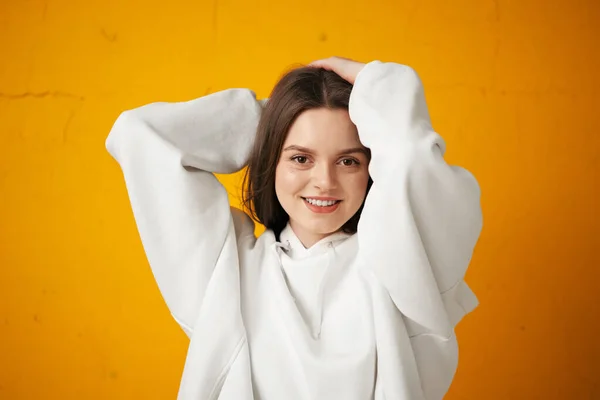 Retrato de una joven estudiante guapa con capucha blanca, ropa casual contra una pared de hormigón naranja . —  Fotos de Stock