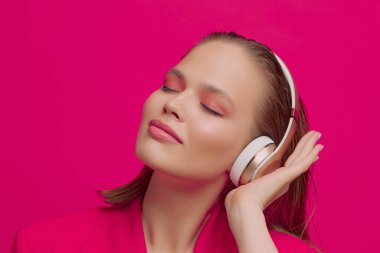 Kablosuz kulaklıklı güzel bir genç kız neşeli bir şekilde şarkı dinler. parlak renkli müzik afişi.