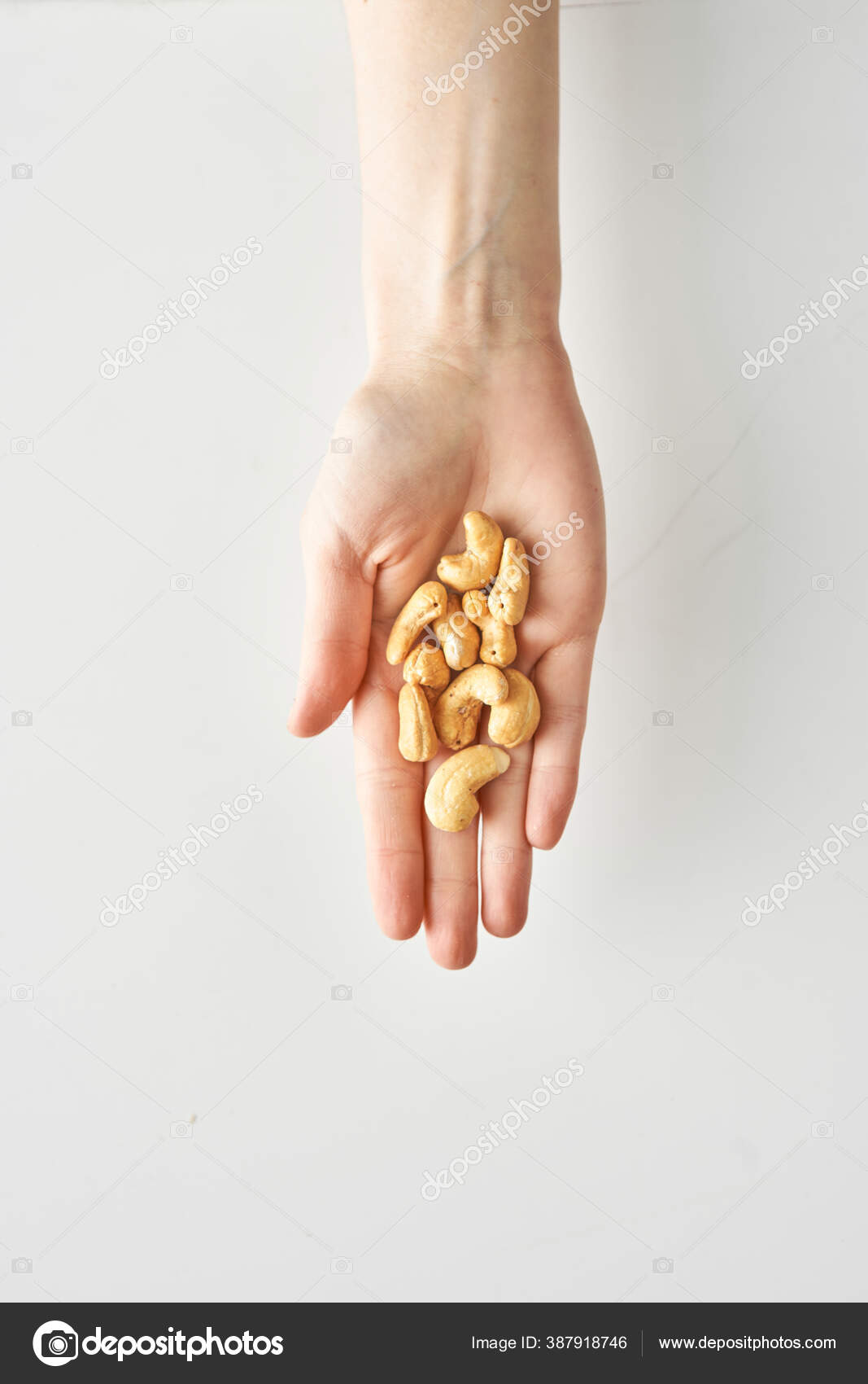 100 calories portion of cashews in a womans hand isolated on a white