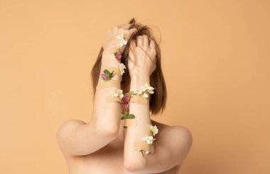 Yüzü çiçek ve alçıyla kaplayan güzel bir genç kız feminist ya da güzellik blogu için konsept fotoğraf.