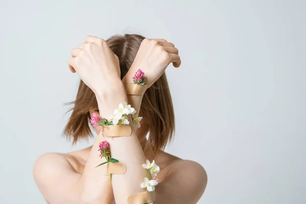 Jolie jeune fille couvrant le visage avec des mains avec des fleurs et des plâtres, concept photo pour féministe ou blog de beauté — Photo