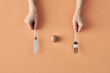 Bej arka planda izole edilmiş çatal ve bıçaklı ceviz ve eller sağlıklı atıştırmalık, yemek blogu veya reklam için kavramsal fotoğraf