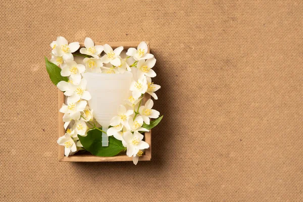 Coupe menstruelle écologique réutilisable et silicone dans une boîte artisanale avec des fleurs isolées sur fond beige — Photo