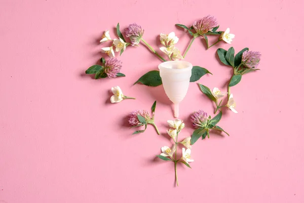 Coupe menstruelle écologique réutilisable et silicone et fleurs en forme de coeur isolé sur un fond rose — Photo