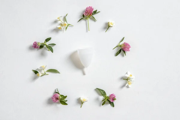 Coupe menstruelle silicone réutilisable respectueux de l'environnement et fleurs isolées sur un fond blanc, photographie pour un blog de femmes — Photo