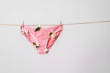 Çamaşır ipinde çiçekler olan pembe kadın iç çamaşırları feminist blog için konsept içeriği, kadın sağlığı hakkında poster