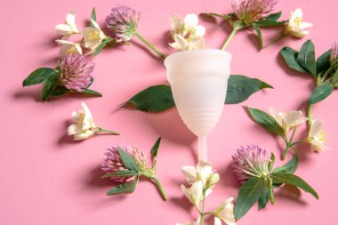 Adet bardağı çevre dostu, yeniden kullanılabilir, silikon ve kalp şeklinde çiçekler pembe arka planda izole edilmiş.