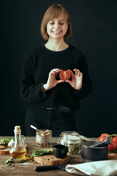 Happy cute girl cooks healthy food in the kitchen. Tomato in hand. Lifestyle food blog content. Healthy diet.