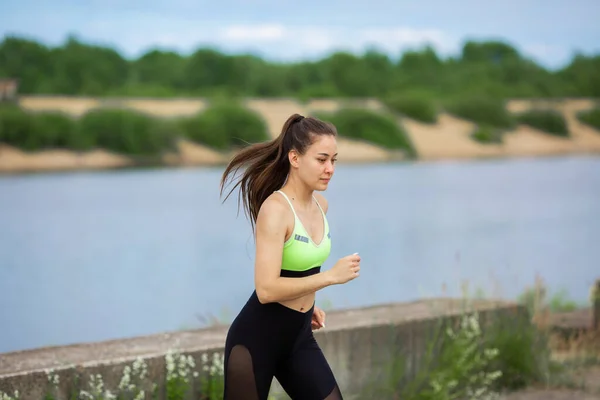 Mujer bastante atlética en ropa deportiva elegante corriendo en la naturaleza, fotografía para blog o anuncio de deporte y estilo de vida saludable — Foto de Stock