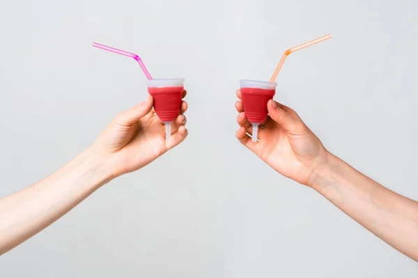 Tazze mestruali eco friendly riutilizzabili e silicone nelle mani delle donne isolate su sfondo bianco con tubi cocktail — Foto Stock