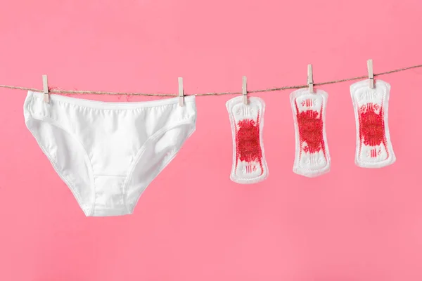 Kadın pedleri ve iç çamaşırları pembe arka planda çamaşır ipinde. Bir kadın için konsept fotoğraf veya feminist blog veya reklam — Stok fotoğraf