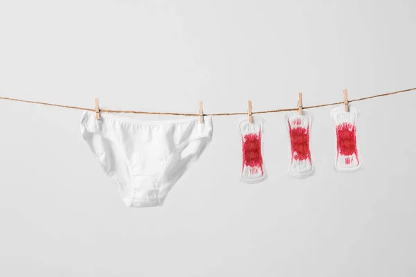 Kadın pedleri ve iç çamaşırları beyaz arka planda çamaşır ipinde. Bir kadın için konsept fotoğraf veya feminist blog veya reklam — Stok fotoğraf