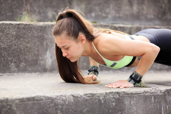 Jeune fille sportive push-ups du sol dans les escaliers de la ville, photographie pour une femme mode de vie sain ou blog de sport — Photo