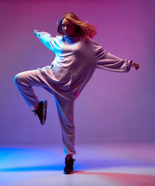 Stylowa młoda dziewczyna, fajny taniec w kapturze z rozwijającymi się włosami, na neonowym tle. Plakat szkoły tańca — Zdjęcie stockowe