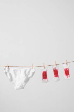 Kadın pedleri ve iç çamaşırları beyaz arka planda çamaşır ipinde. Bir kadın için konsept fotoğraf veya feminist blog veya reklam