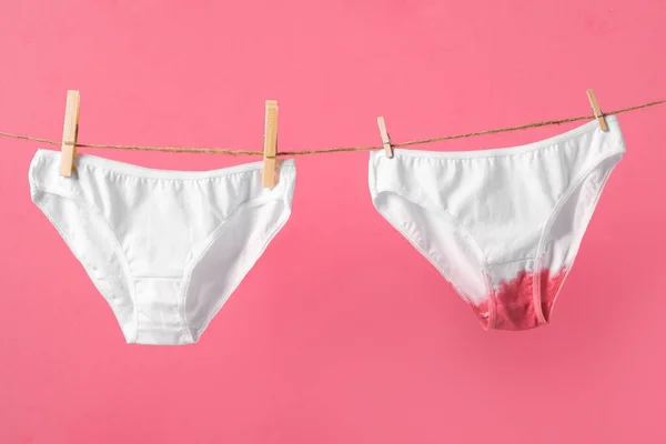Çamaşır ipindeki kadın iç çamaşırları, pembe arka planda izole edilmiş, kadınların sağlığı ve adet görme ile ilgili konsept posteri. — Stok fotoğraf