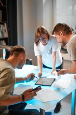 Genç yaratıcı tasarımcılar modern stüdyoda tablet kullanarak yeni bir iç proje geliştiriyorlar.