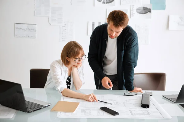 Creative team of architects designers discussing ideas, working in modern office over a laptop