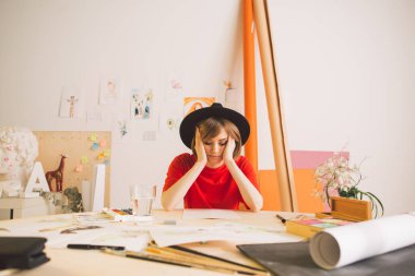 Üzgün kız Illustrator sanatçısı stüdyoda masada otururken kafasını kavradı. Reklam sanatı kursları veya blog için fotoğraf